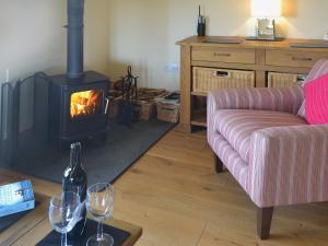 a living room with a fireplace and two glasses of wine at Stanhope Cottage in Lower Boscaswell
