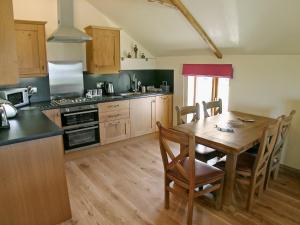 Lower Boscaswell的住宿－Stanhope Cottage，一间带木桌的厨房和一间餐厅