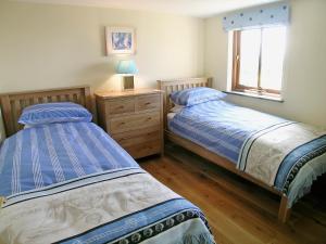 Lower Boscaswell的住宿－Stanhope Cottage，一间卧室设有两张床和窗户。