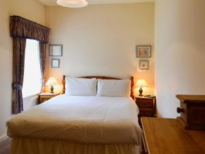 ein Schlafzimmer mit einem großen Bett mit zwei Nachttischen und zwei Lampen in der Unterkunft Lavender Cottage-mgg in Akeld