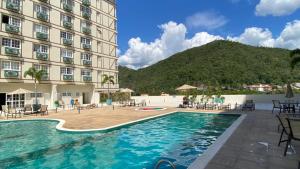 een hotel met een zwembad en een berg op de achtergrond bij Estudio Itaipava - Granja Brasil - Flat Luxo 419 - Piscina Aquecida in Itaipava