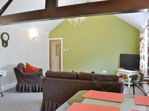 a living room with a couch and a tv at Granary Cottage in Penrhyn Bay