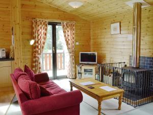 a living room with a red couch and a stove at Larch Cottage - S4428 in Kirkton of Glenisla