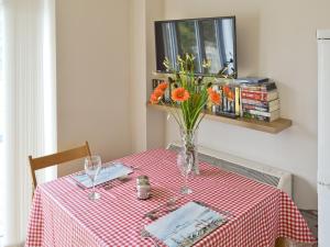 stół z wazonem z pomarańczowymi kwiatami w obiekcie Baytree Cottage 2 w mieście Birch