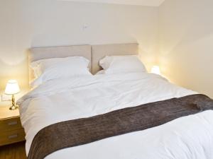uma grande cama branca com lençóis e almofadas brancos em Baytree Cottage 2 em Birch