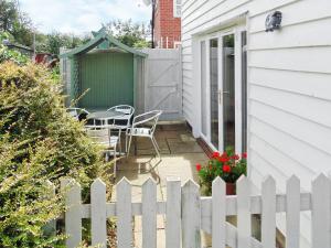 ein weißer Zaun neben einem Haus mit einem Tisch und Stühlen in der Unterkunft Baytree Cottage 2 in Birch