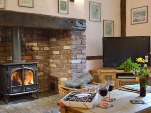 a living room with a fireplace and a television at Henley Bridge Holiday Cottage in Ashburnham