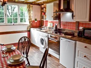 a kitchen with a washing machine and a table with chairs at Henley Bridge Holiday Cottage in Ashburnham