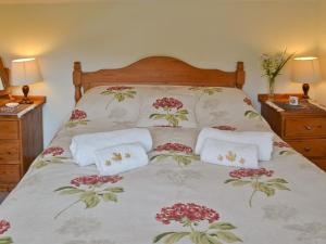 Henley Bridge Holiday Cottage في Ashburnham: سرير عليه مناشف بيضاء وزهور