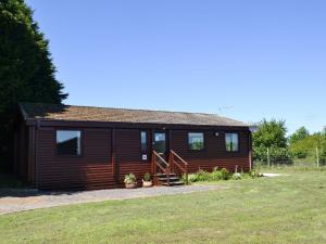 a log cabin with a porch and a yard at Hartland Forest Golf Leisure in Woolfardisworthy
