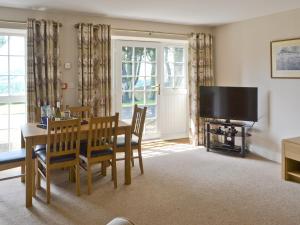 a dining room with a table and a television at Plover Cottage in Sharperton