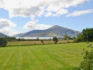 a field with a lake and mountains in the background at Loch Alsh Cottage - Uvo in Balmacara