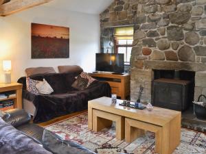 a living room with couches and a stone fireplace at Glanrafon Isaf in Llanwnda