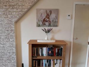 a book shelf with a picture of a rabbit on the wall at Wren Cottage in Longhorsley
