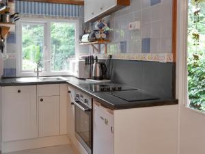 a kitchen with white cabinets and a sink and a window at Trewartha-by-chy in Crackington Haven