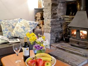una mesa con una bandeja de fruta y una botella de vino en The Thatch Cottage en South Petherwin