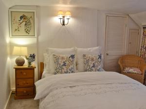 1 dormitorio con 1 cama blanca con almohadas y lámpara en The Thatch Cottage en South Petherwin