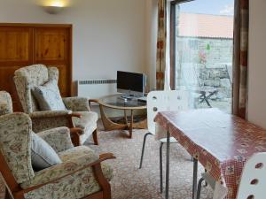 a living room with chairs and a table and a television at Maddy Cart House in Commondale