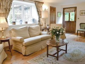 een woonkamer met een bank en een vaas met bloemen op een tafel bij Grooms Cottage in Westleigh