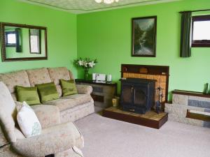 uma sala de estar com um sofá e uma lareira em The Cottage em Poolewe