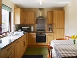uma cozinha com armários de madeira e um forno com placa de fogão em The Cottage em Poolewe
