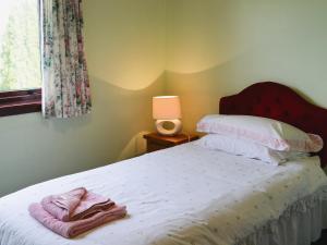 um quarto com uma cama, um candeeiro e uma janela em The Cottage em Poolewe
