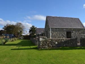 an old stone building in a field with green grass at Dwyfach in Llanystumdwy