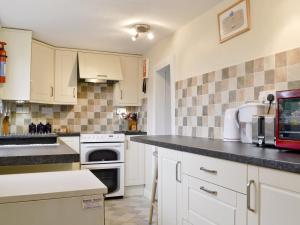 a kitchen with white cabinets and a black counter top at Bay House in Sculthorpe