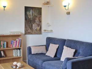Sofá azul en la sala de estar con estantería en Natterjack Cottage en Haverigg