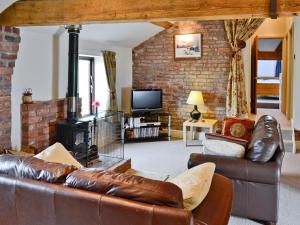 a living room with leather furniture and a brick wall at The Old Stables in Helsby