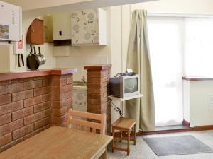 a kitchen with a brick wall and a tv at Ottery Tor - Ukc1925 in Stokeinteignhead