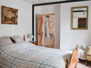 オールストンにあるThe Coachman's Cottageのベッドルーム1室(ベッド1台、壁掛け鏡付)
