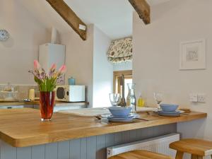 a kitchen with a counter with a vase of flowers on it at The Vestry in Cyffic