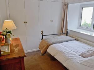 1 dormitorio con cama, mesa y ventana en Mill Cottage, en Winterborne Steepleton