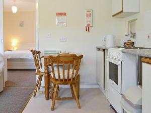 una cucina con 2 sedie, un tavolo e un piano cottura di Rose Cottage - B6009 a Wendling