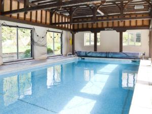 a large swimming pool with blue water in a building at Rose Cottage - B6009 in Wendling