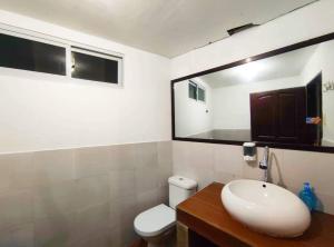 een badkamer met een wastafel, een toilet en een spiegel bij Bungalow in Holidays Beach Resort in Bolinao