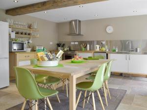 a kitchen with a wooden table and green chairs at West Barn in Chesterfield