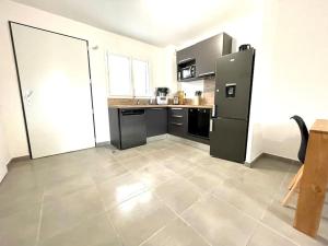 a kitchen with a black refrigerator and a tile floor at Villa 8 personnes bord de mer climatisée in Saintes-Maries-de-la-Mer