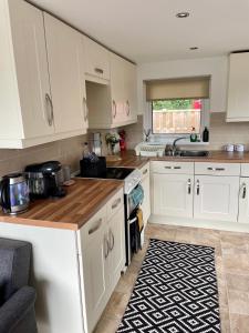 a kitchen with white cabinets and a wooden counter top at Moonlight Lodge in Caeathro