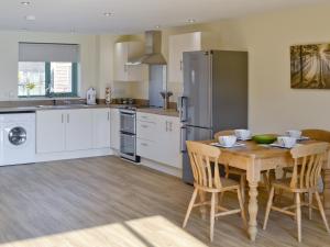 a kitchen with a wooden table and a refrigerator at Kingfisher Lodge in Hainford