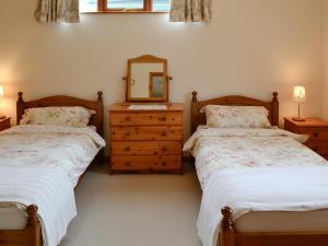 two beds in a room with a mirror and a dresser at The Old Cowshed in Broadway