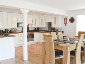 a kitchen with white cabinets and a table and chairs at The Old Granary in Ballindalloch