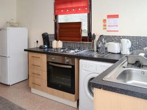 a kitchen with a sink and a stove and a dishwasher at Kimberly Cottage in Alness