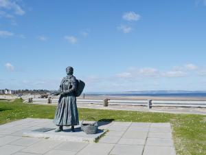 Eine Statue einer Frau, die neben dem Strand steht. in der Unterkunft Kimberly Cottage in Alness