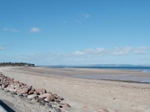 a beach with rocks on the sand and water at Kimberly Cottage in Alness