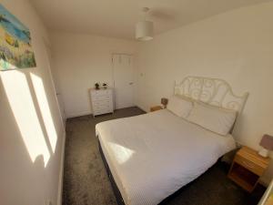sypialnia z białym łóżkiem i komodą w obiekcie Teddy Bears' 3-bedroom Maisonette w mieście Saltcoats
