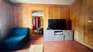uma sala de estar com um sofá azul e uma televisão de ecrã plano em PredazzoHouse em Predazzo