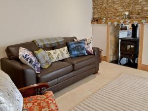 um sofá de couro castanho numa sala de estar com uma mesa em Manor House Dairy Cottage em Ayton
