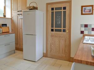 um frigorífico branco numa cozinha com uma porta em Manor House Dairy Cottage em Ayton